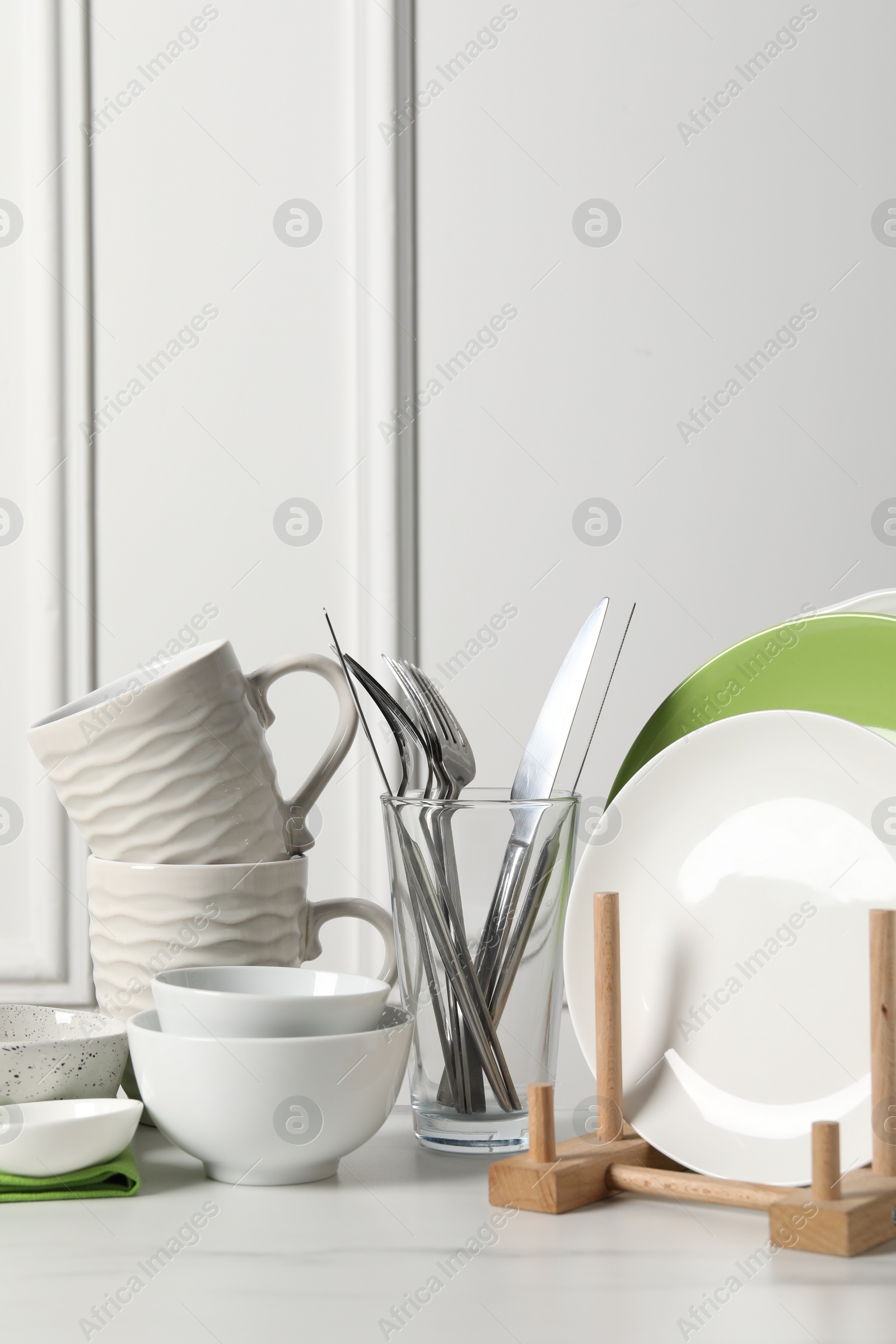 Photo of Beautiful ceramic dishware, cups and cutlery on white marble table