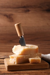 Photo of Delicious parmesan cheese with knife on wooden table