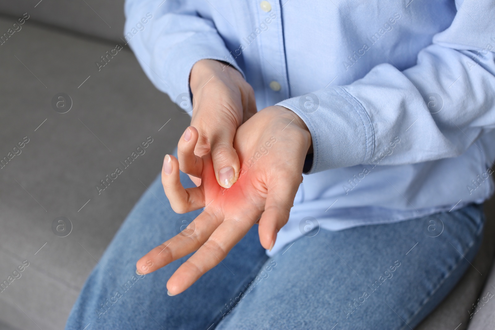 Image of Woman suffering from trigger finger on sofa, closeup