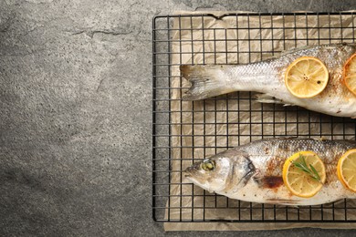 Baked fish with lemon on grey textured table, top view. Space for text