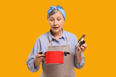 Photo of Housewife with pot and lid on orange background
