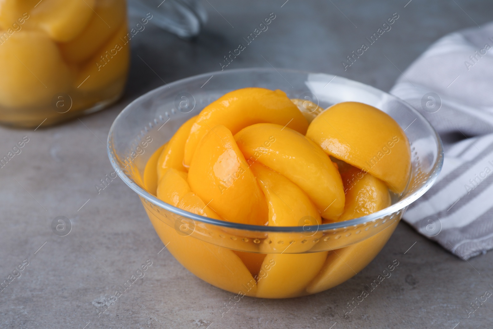 Photo of Canned peach halves in glass bowl on grey table