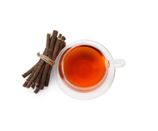 Photo of Aromatic licorice tea in cup and dried sticks of licorice root isolated on white, top view