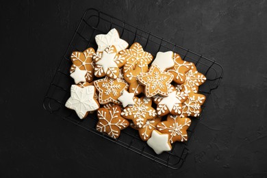 Photo of Tasty Christmas cookies with icing on black table, top view