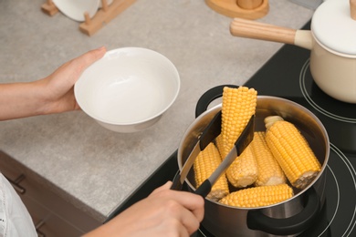 Photo of Woman preparing corn in stewpot on stove, closeup