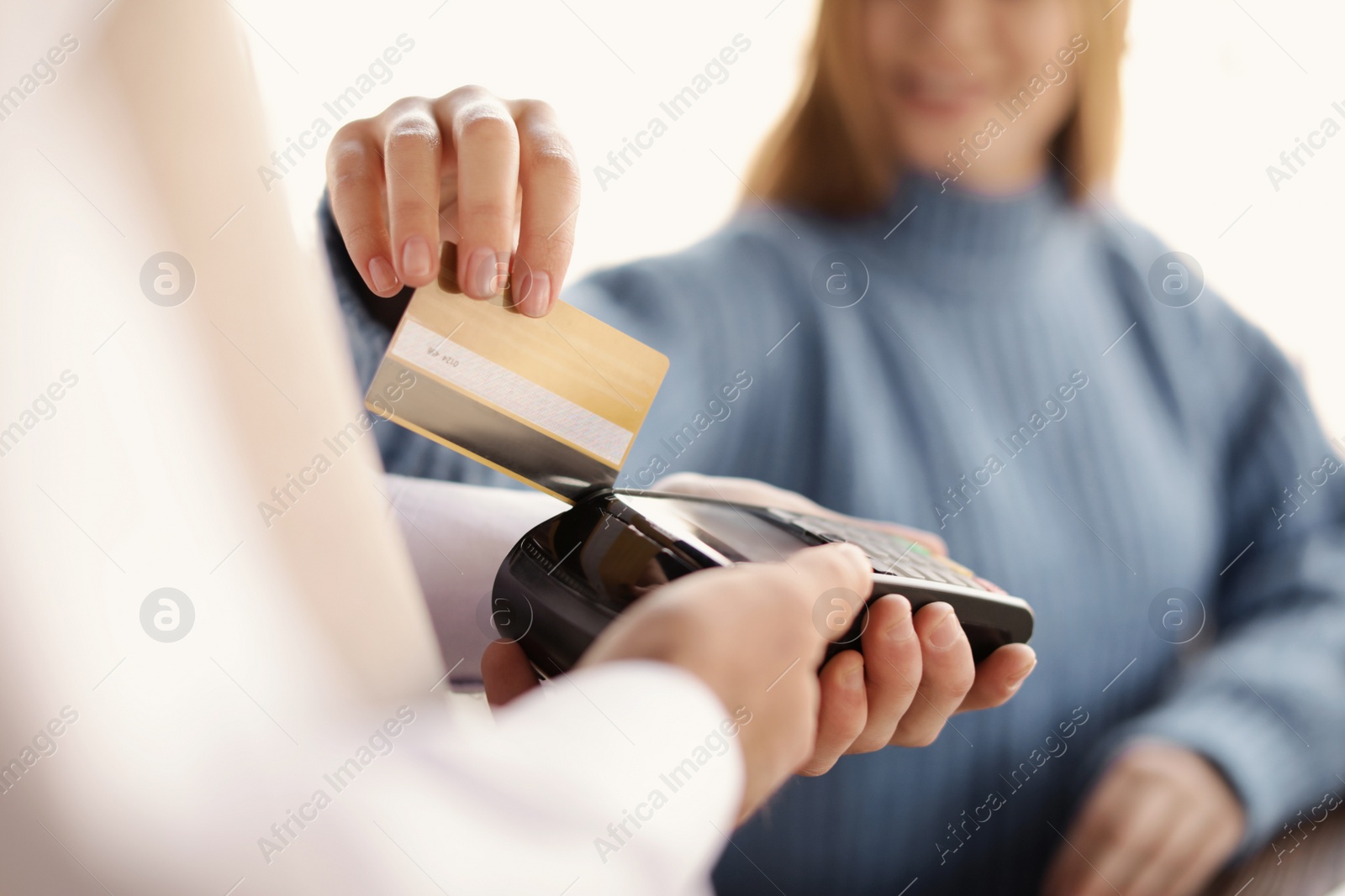 Photo of Woman with credit card using payment terminal at restaurant, closeup