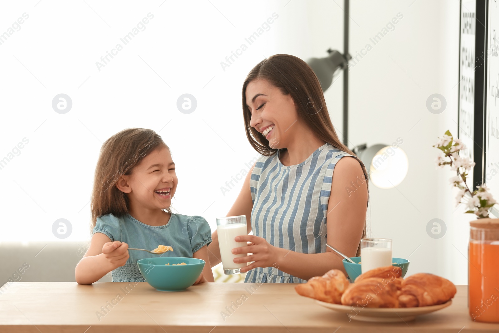 Photo of Mother and daughter having breakfast with milk at table