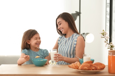 Mother and daughter having breakfast with milk at table