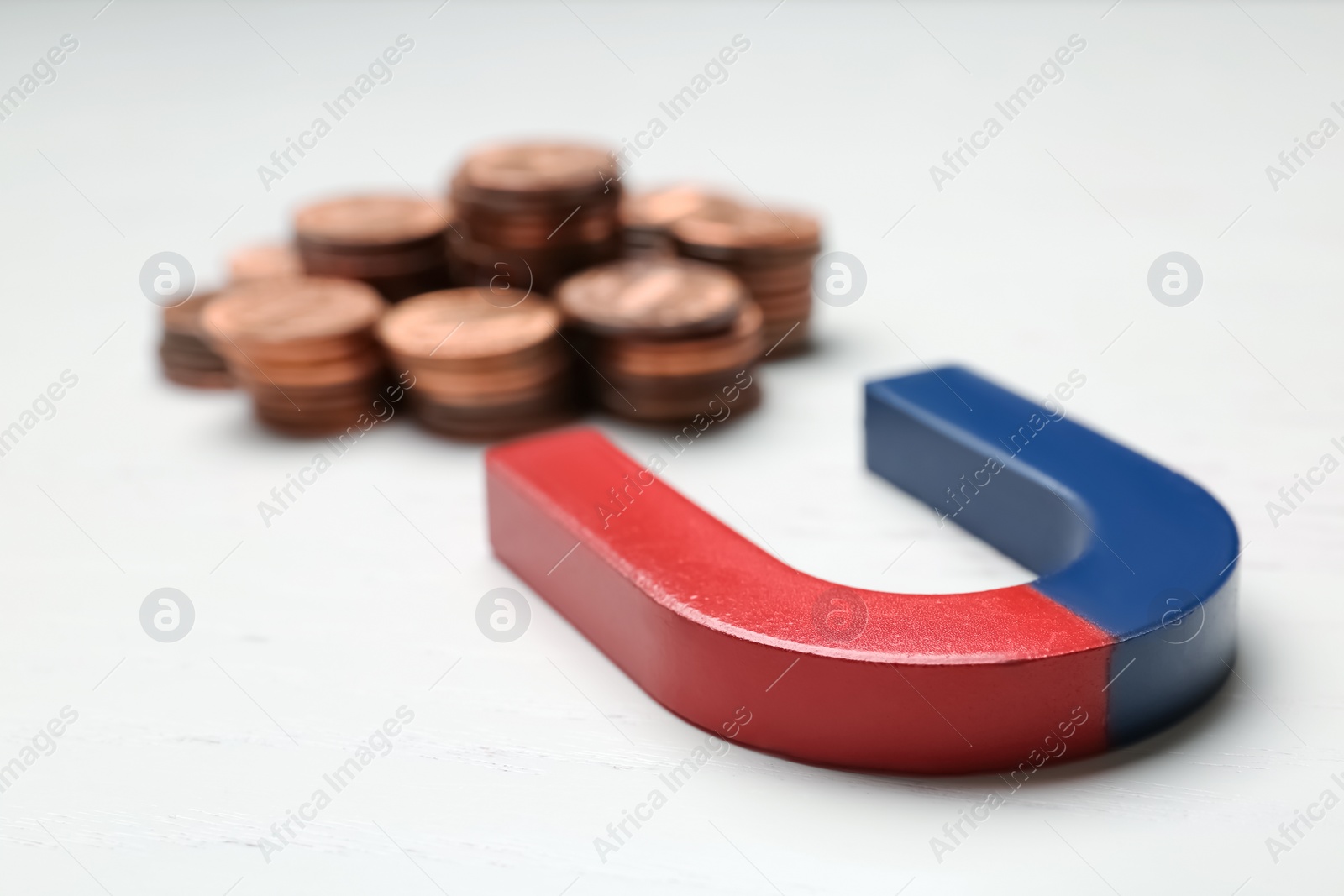 Photo of Magnet attracting coins on wooden background. Business concept