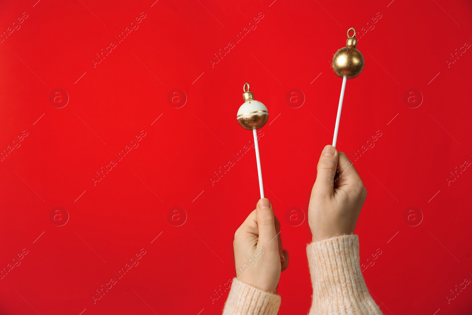Photo of Woman holding delicious Christmas themed cake pops against pink background, closeup. Space for text