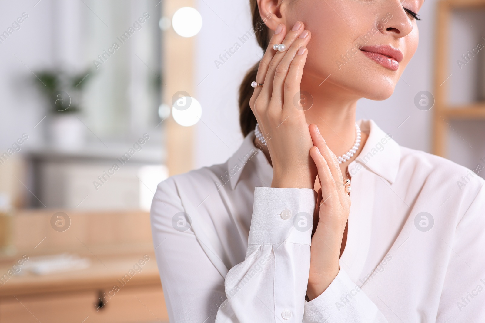 Photo of Young woman wearing elegant pearl jewelry indoors, closeup. Space or text