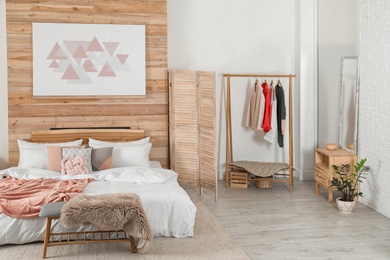 Photo of Stylish room interior with comfortable bed near wooden wall