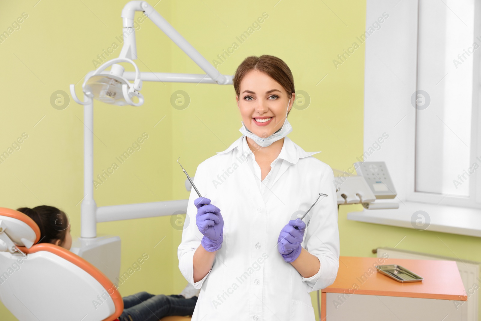 Photo of Professional dentist with tools and patient in modern clinic