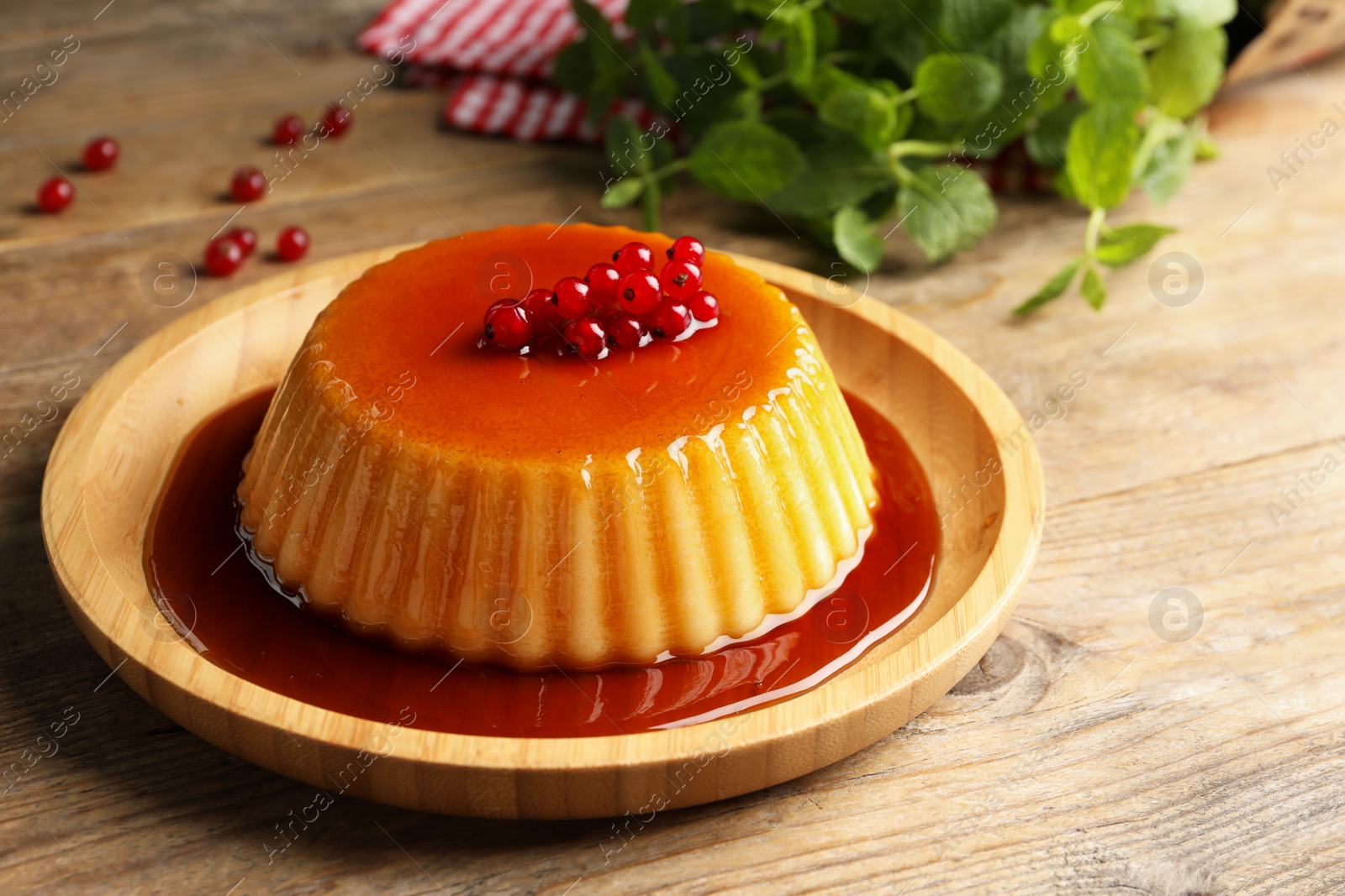 Photo of Delicious pudding with caramel, redcurrants on wooden table