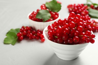 Photo of Delicious red currants in bowl on light table. Space for text