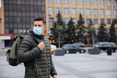 Photo of Man in medical face mask walking outdoors. Personal protection during COVID-19 pandemic