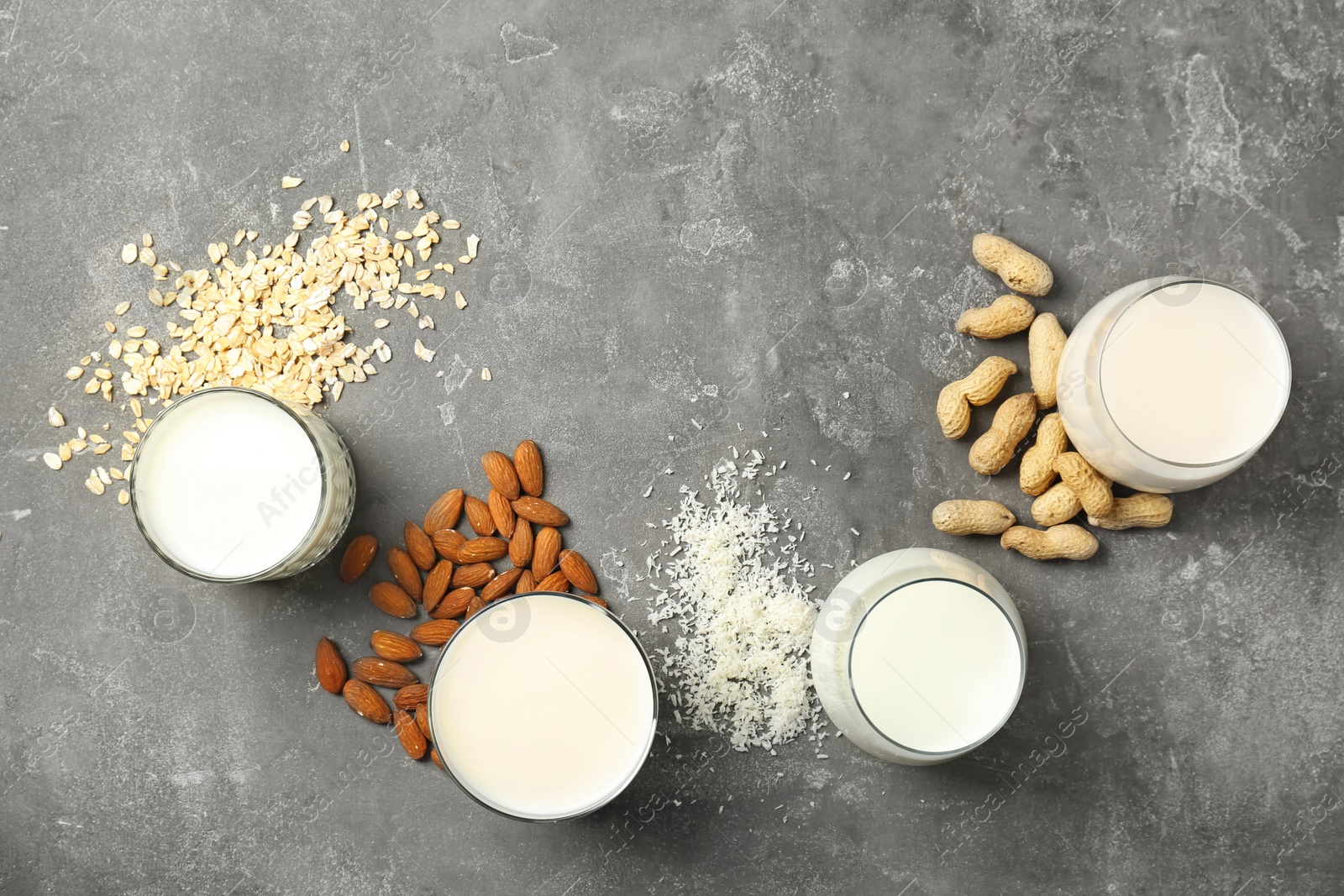 Photo of Glasses with different types of milk and ingredients on grey background