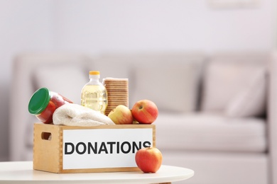 Photo of Donation box with food products on table indoors