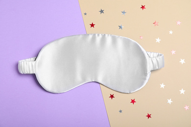 Photo of White sleeping mask and glitter on color background, flat lay. Bedtime accessory