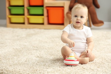 Photo of Children toys. Cute little boy and spinning top on rug at home, space for text