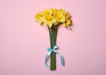 Photo of Bouquet of beautiful yellow daffodils on pink background, top view