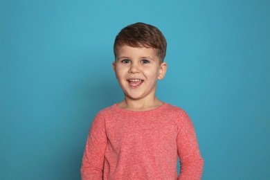 Portrait of little boy laughing on color background