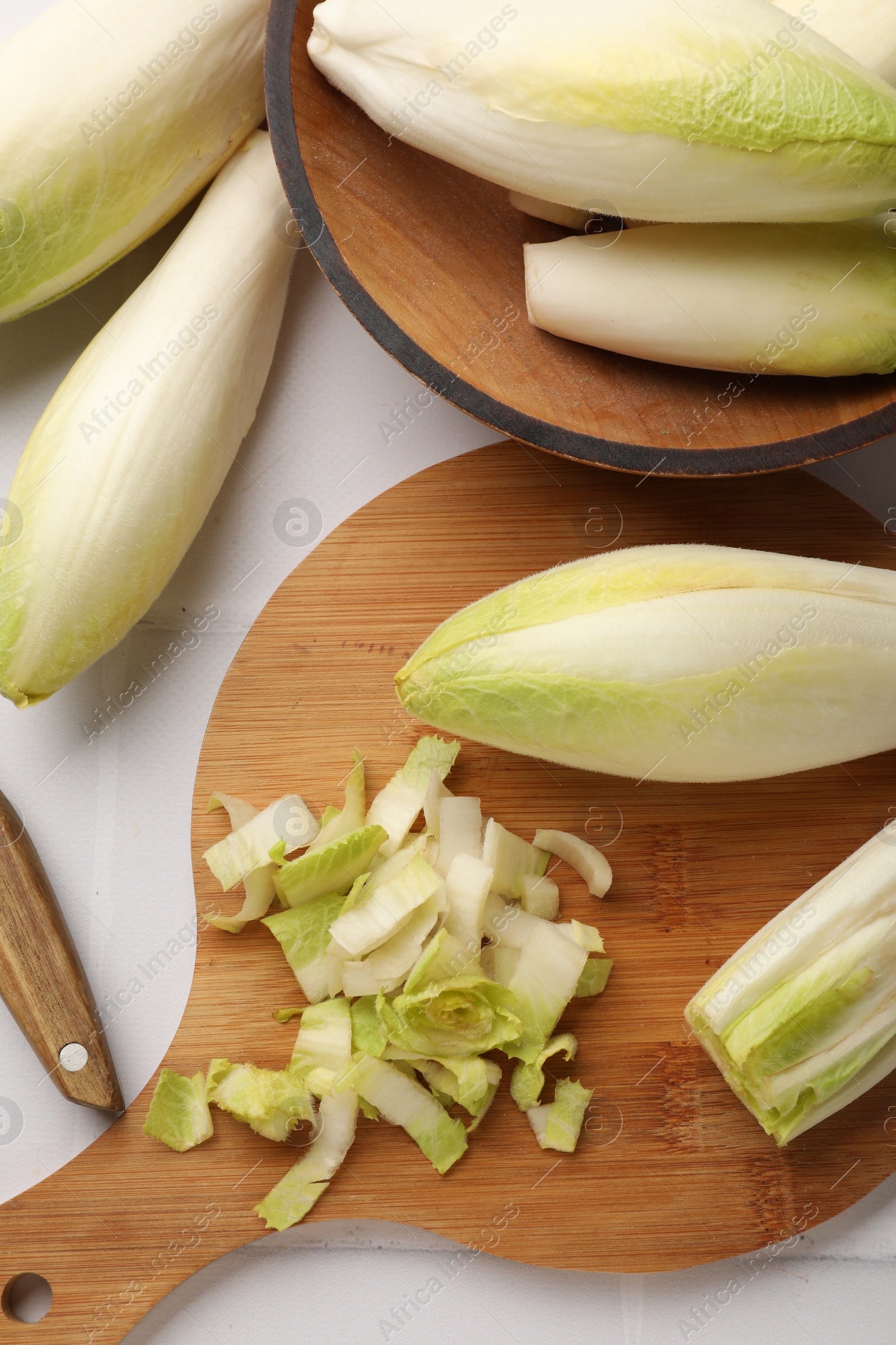 Photo of Fresh raw Belgian endives (chicory) on white tiled table, flat lay