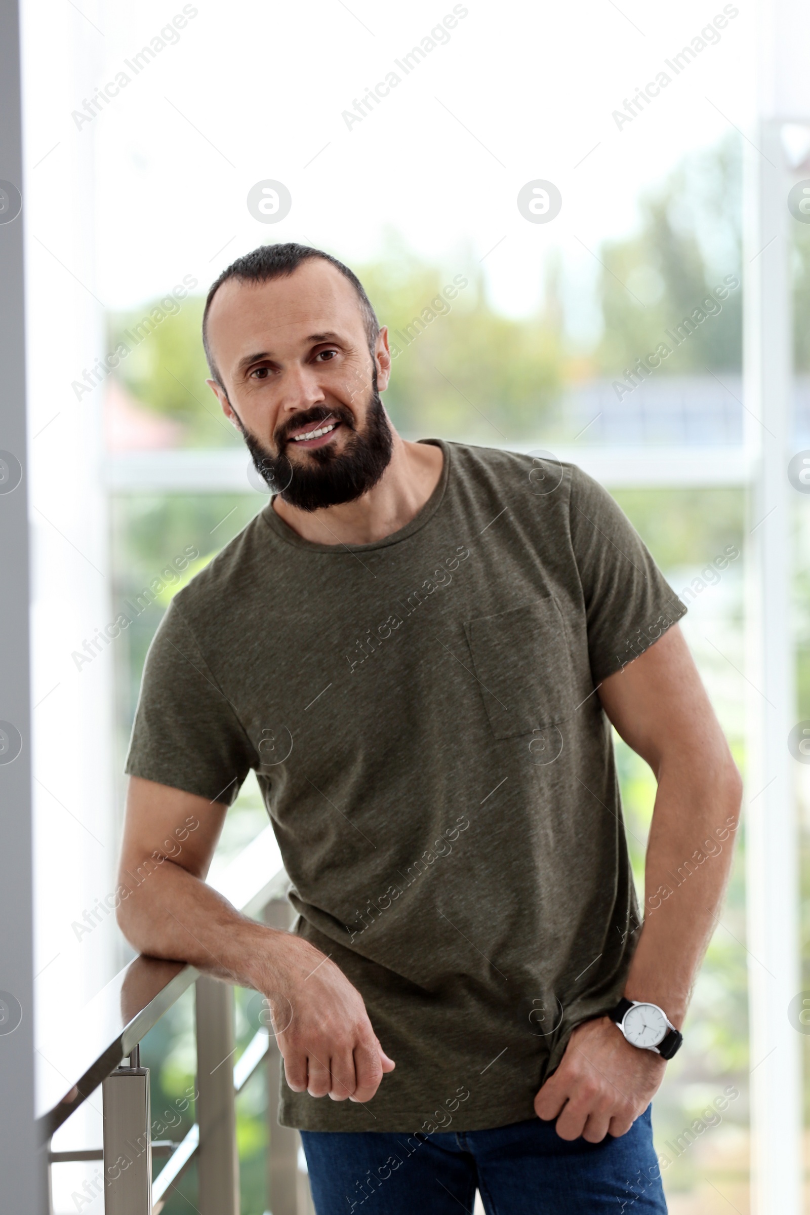 Photo of Portrait of handsome mature man leaning on handrail indoors