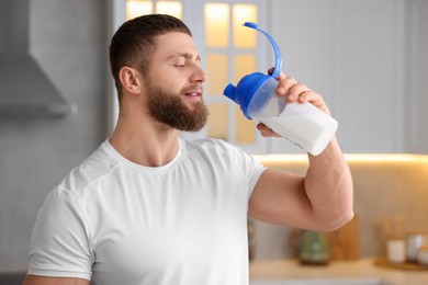 Photo of Young man with shaker of protein in kitchen