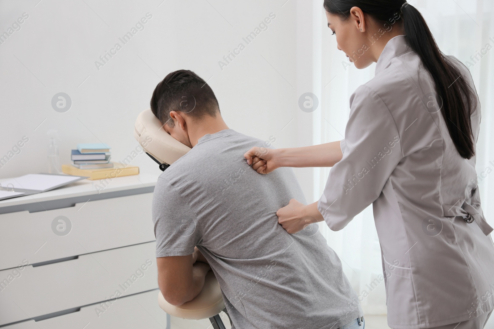 Photo of Man receiving massage in modern chair indoors