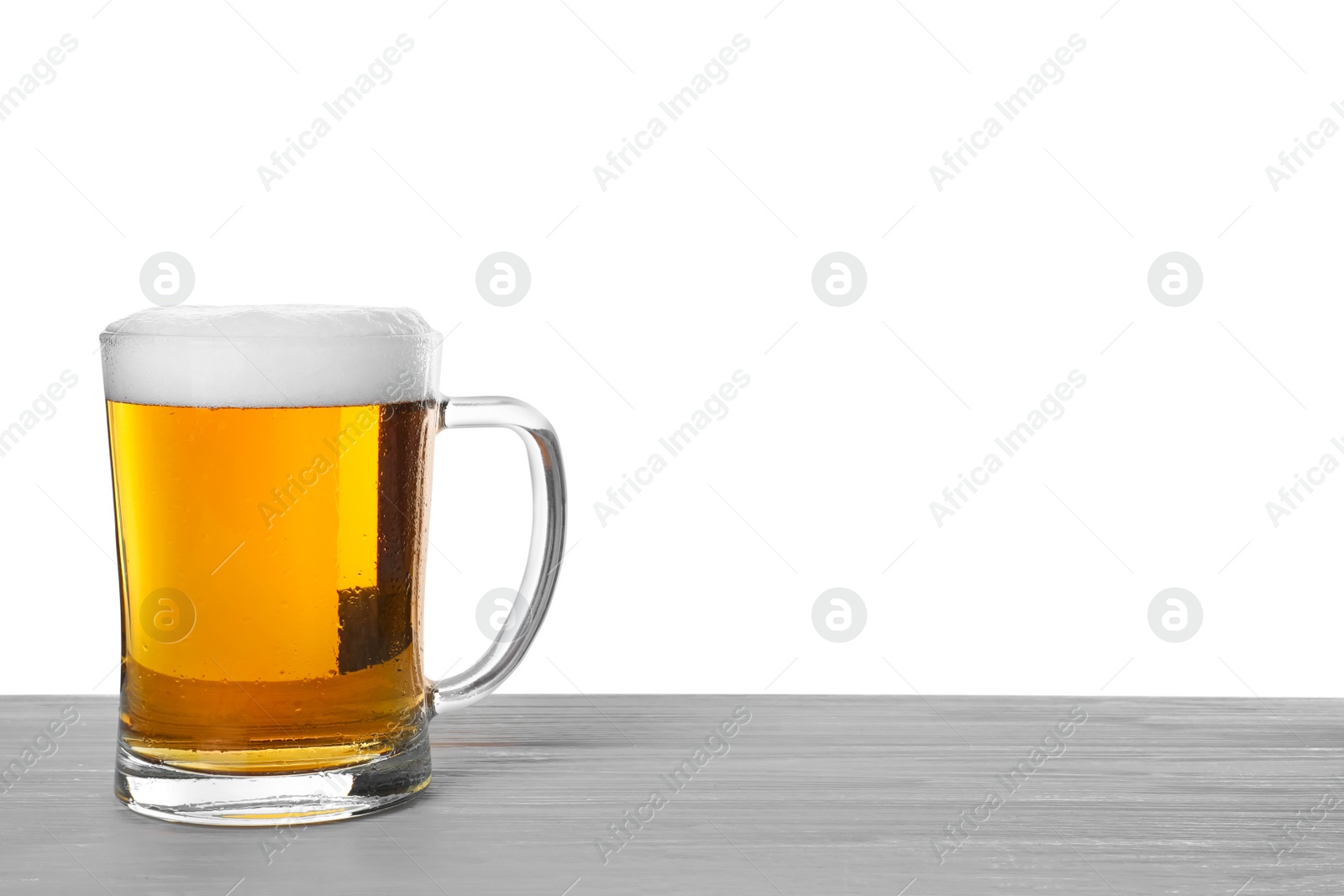 Photo of Glass mug of tasty beer on wooden table against white background