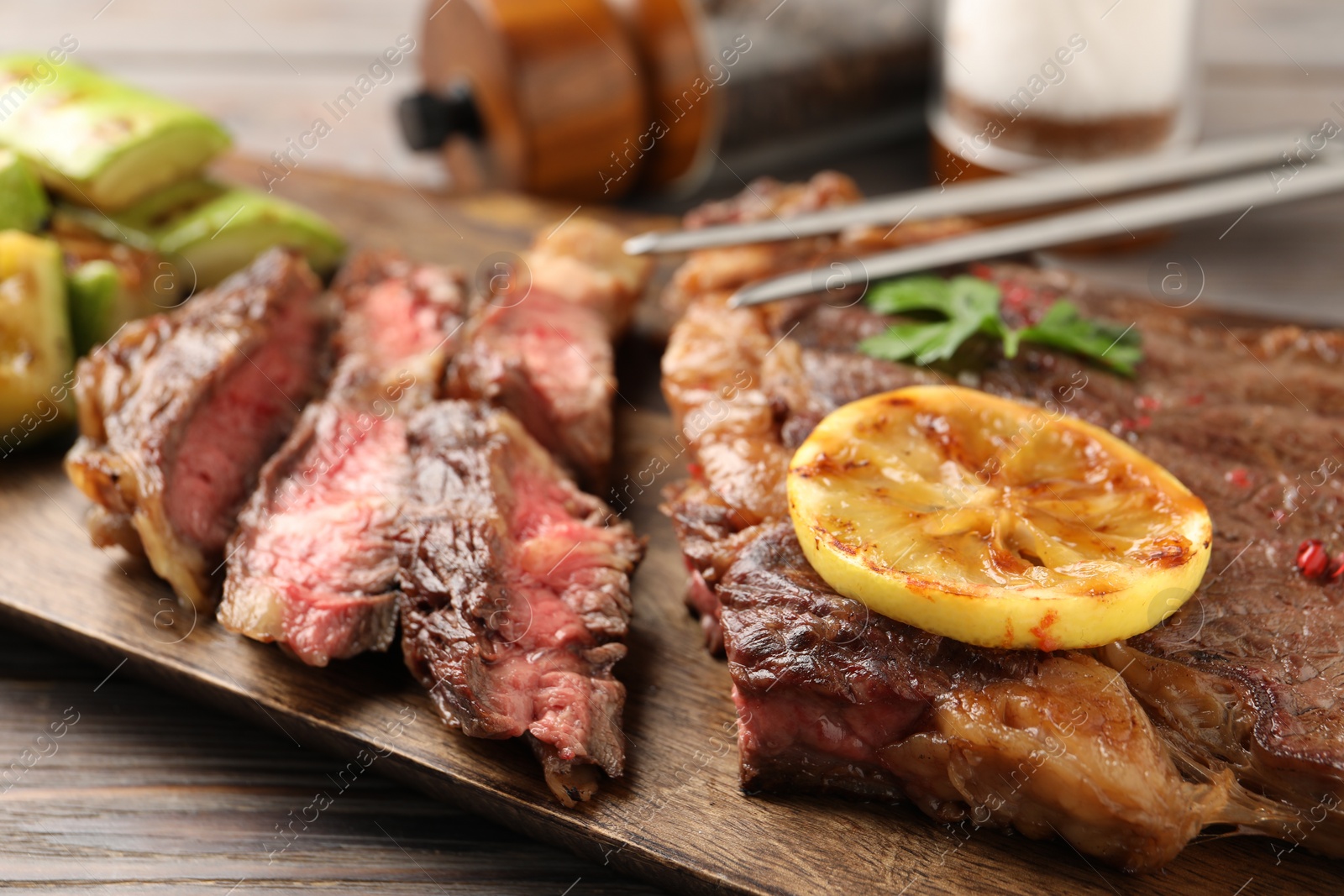 Photo of Delicious grilled beef steak on wooden table, closeup