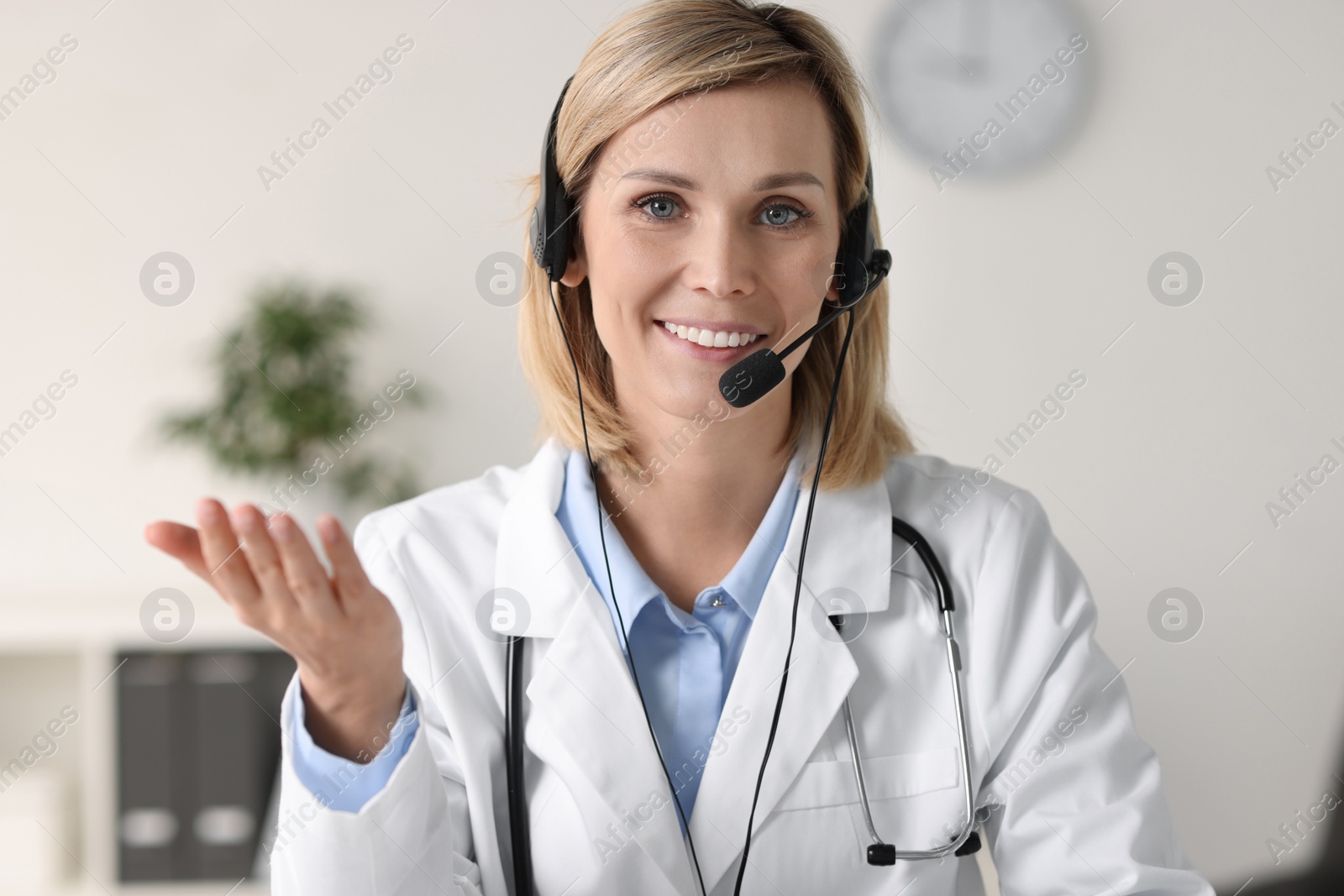 Photo of Smiling doctor wearing headphones having online in office