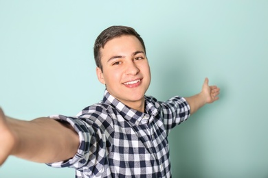 Photo of Young handsome man taking selfie against color background