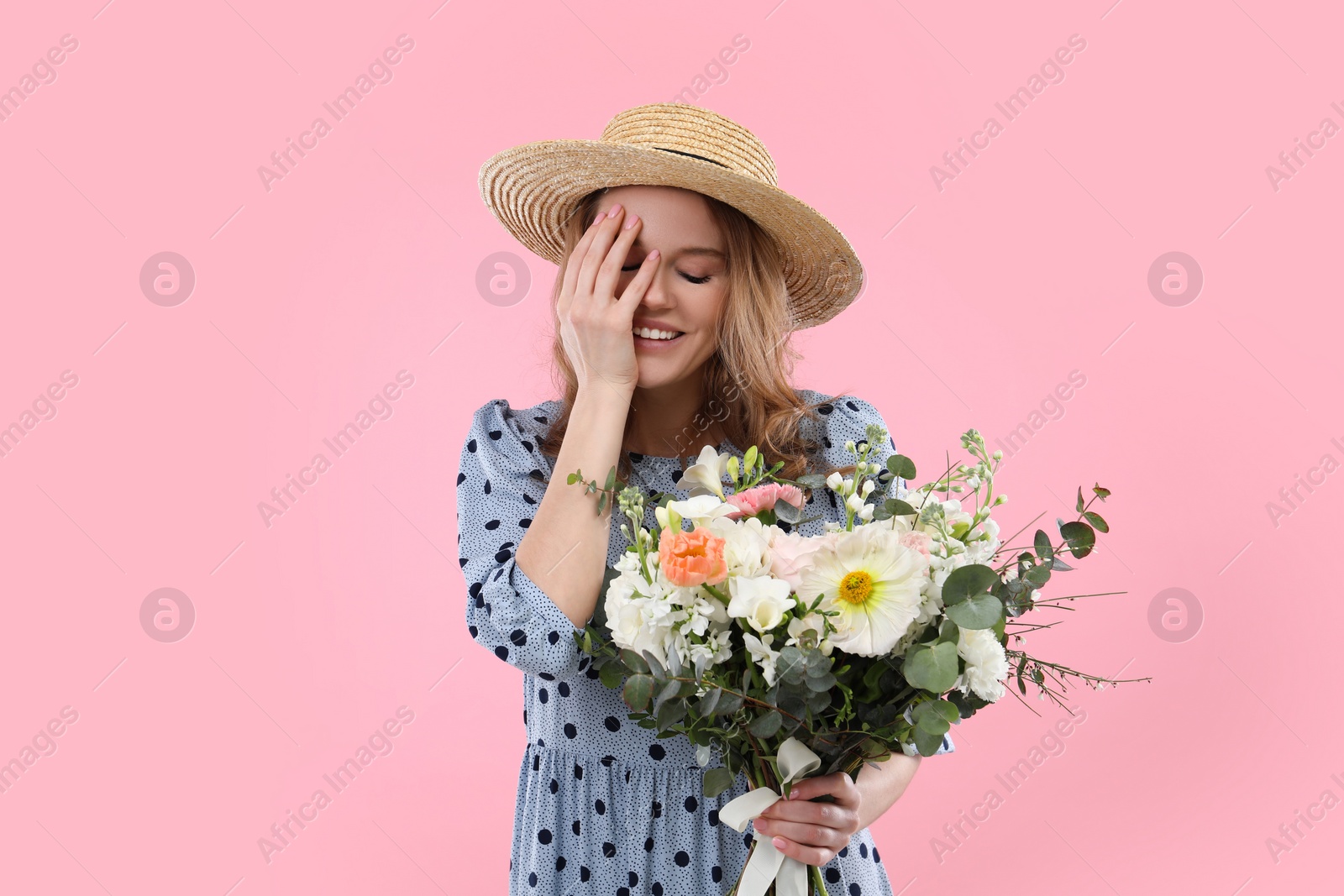 Photo of Beautiful woman in straw hat with bouquet of flowers on pink background