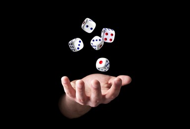 Man throwing white dice on black background, closeup