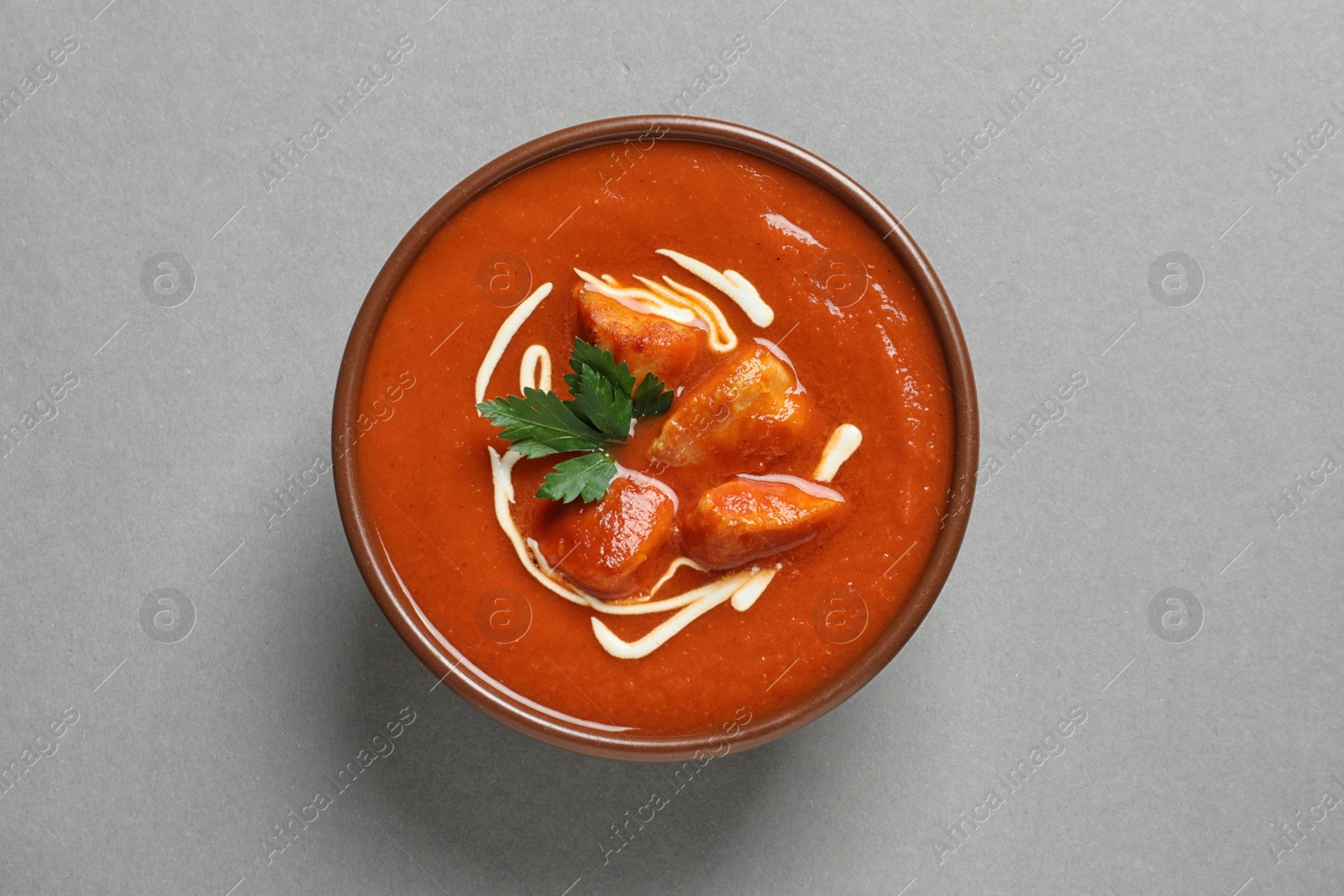 Photo of Bowl of delicious butter chicken on color background, top view. Traditional indian Murgh Makhani