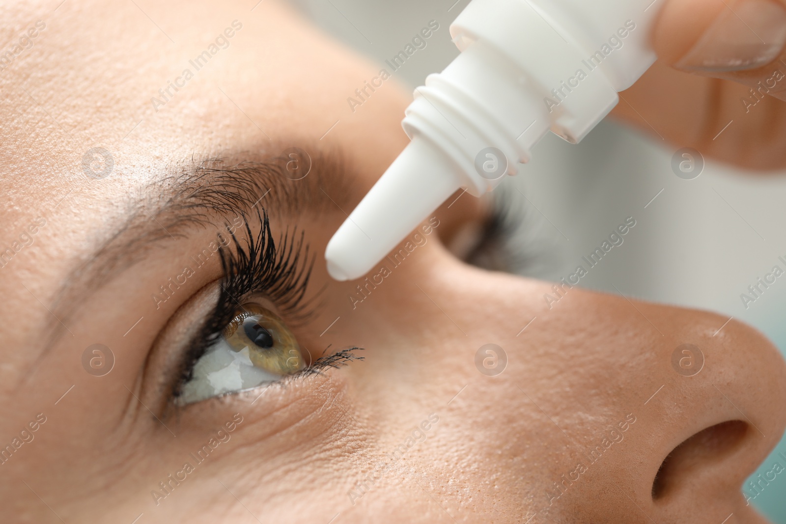 Photo of Woman applying medical eye drops, macro view