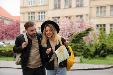 Couple of tourists with map planning trip on city street