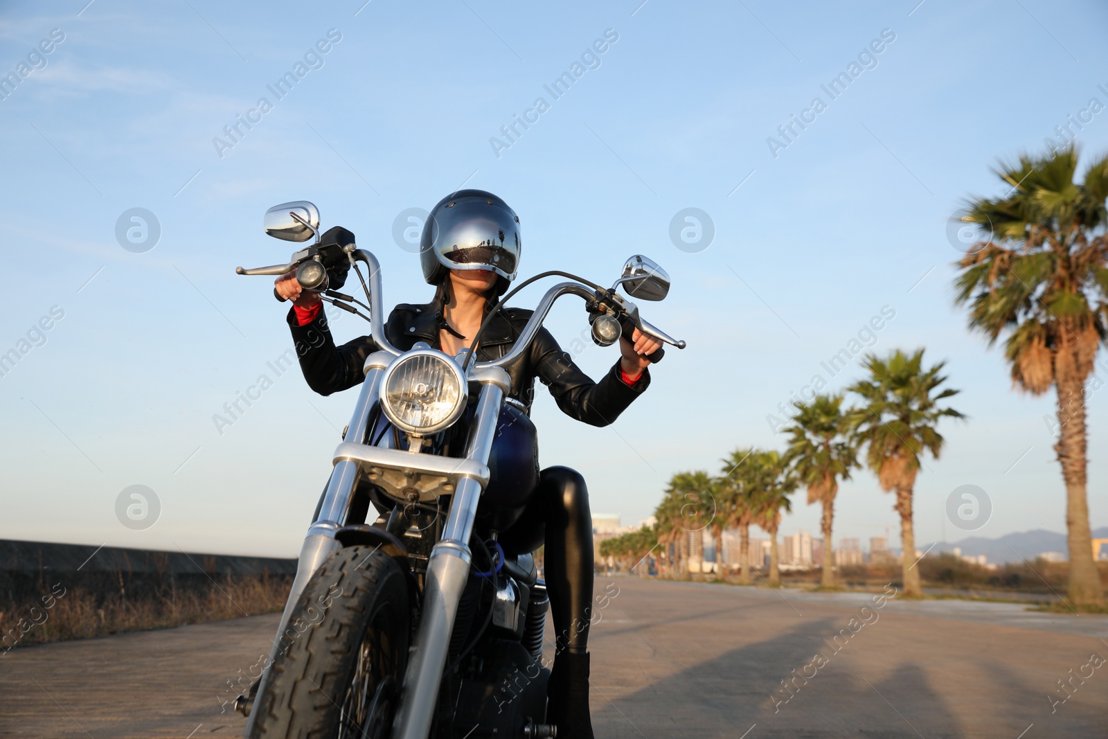 Photo of Woman in helmet riding motorcycle on sunny day