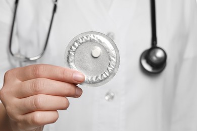 Doctor holding blister of emergency contraception pill, focus on hand