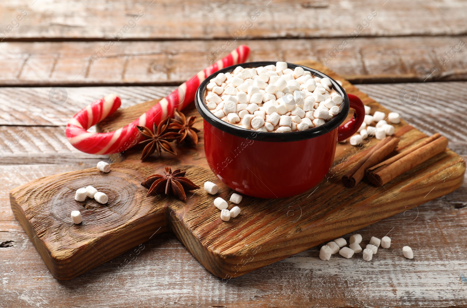 Photo of Tasty hot chocolate with marshmallows and candy cane on wooden table