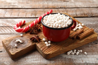 Tasty hot chocolate with marshmallows and candy cane on wooden table