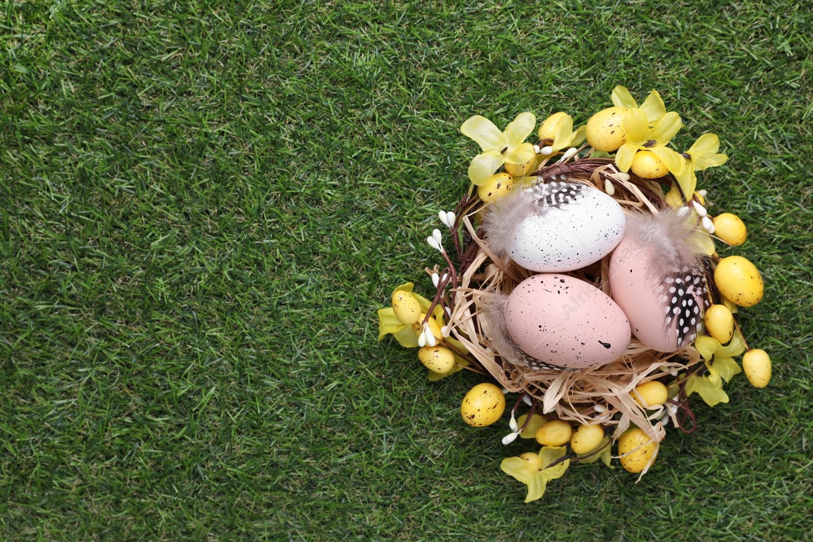 Photo of Festively decorated Easter eggs on green grass, top view. Space for text