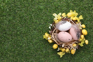 Photo of Festively decorated Easter eggs on green grass, top view. Space for text