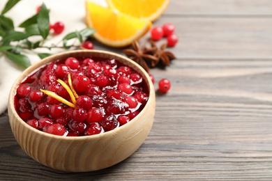 Photo of Fresh cranberry sauce with orange peel on wooden table, space for text