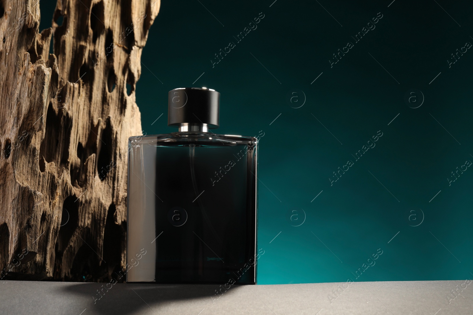 Photo of Luxury men`s perfume in bottle on grey table against color background, space for text