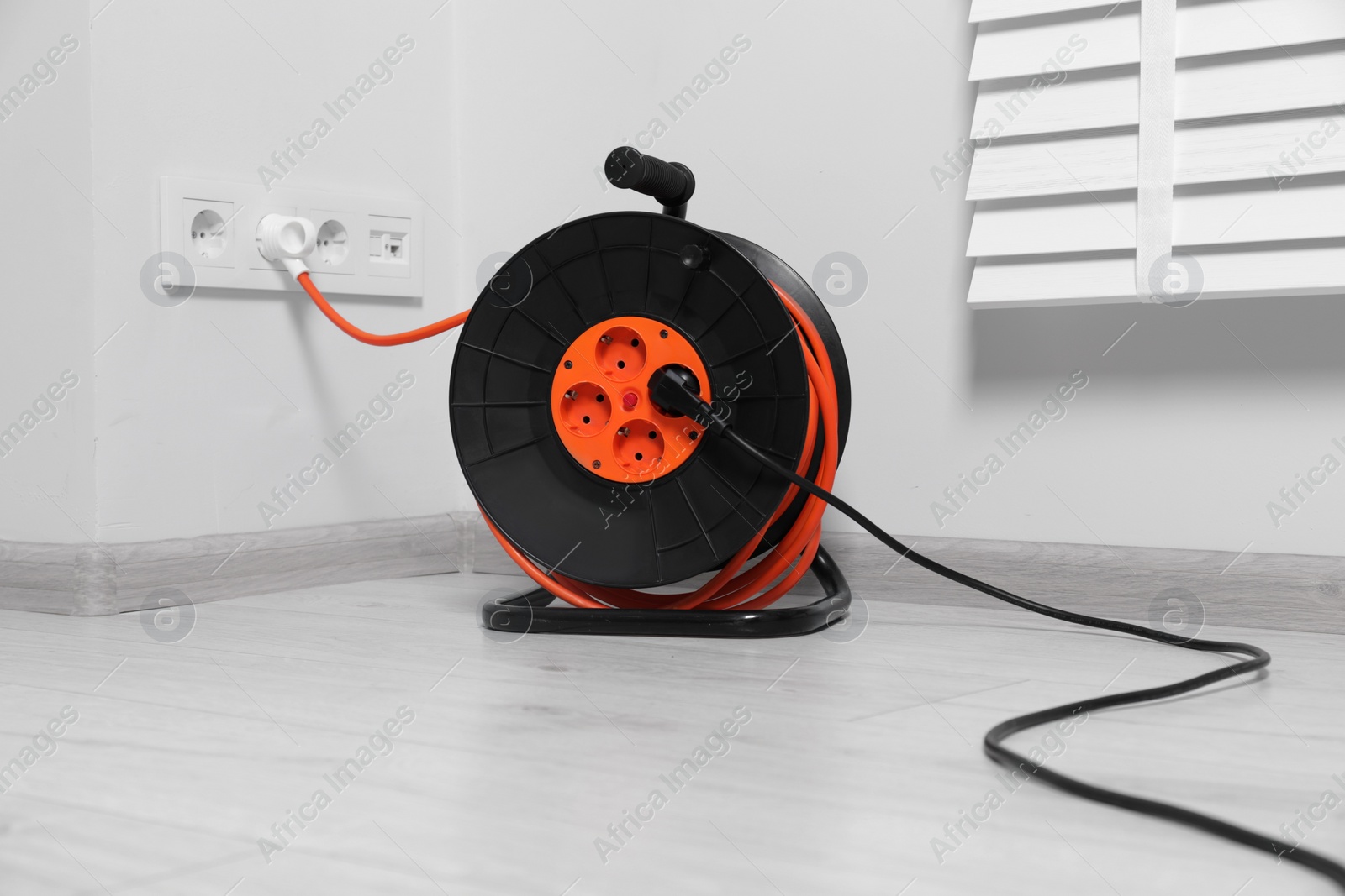 Photo of Extension cord reel plugged into socket indoors. Electrician's equipment