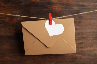 Photo of Envelope and paper heart hanging on twine against wooden background. Love letter