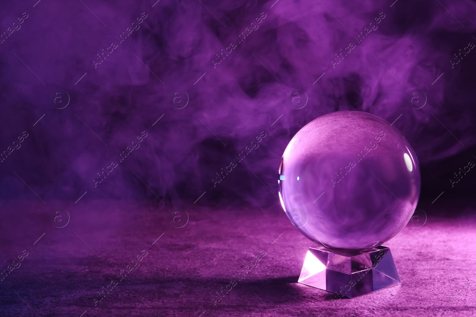 Photo of Crystal ball on table and smoke against dark background, space for text. Predictions of future